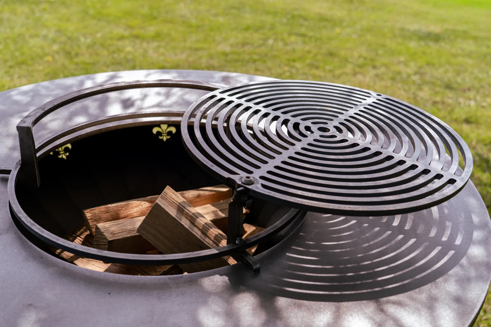 Grille pivotante en acier carbone avec son cerclage anti-chute, au-dessus du foyer du brasero.